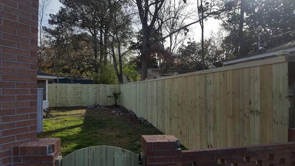 A wooden fence is in the backyard of a house.