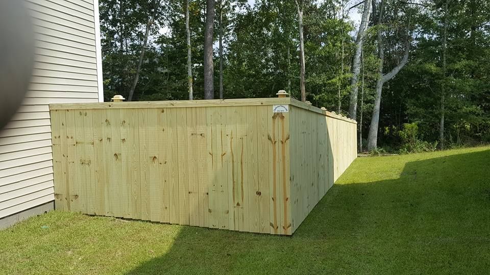 A wooden fence is sitting in the grass next to a house.