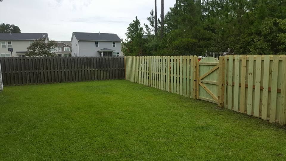 A wooden fence with a gate in the backyard of a house.