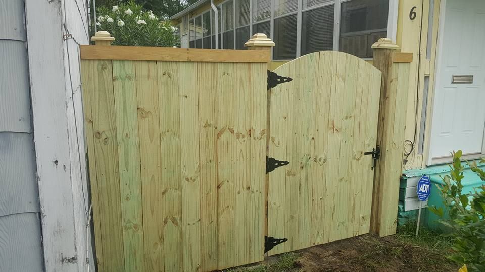 A wooden fence with a gate in front of a house.