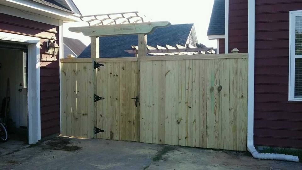 A wooden fence is in front of a red house