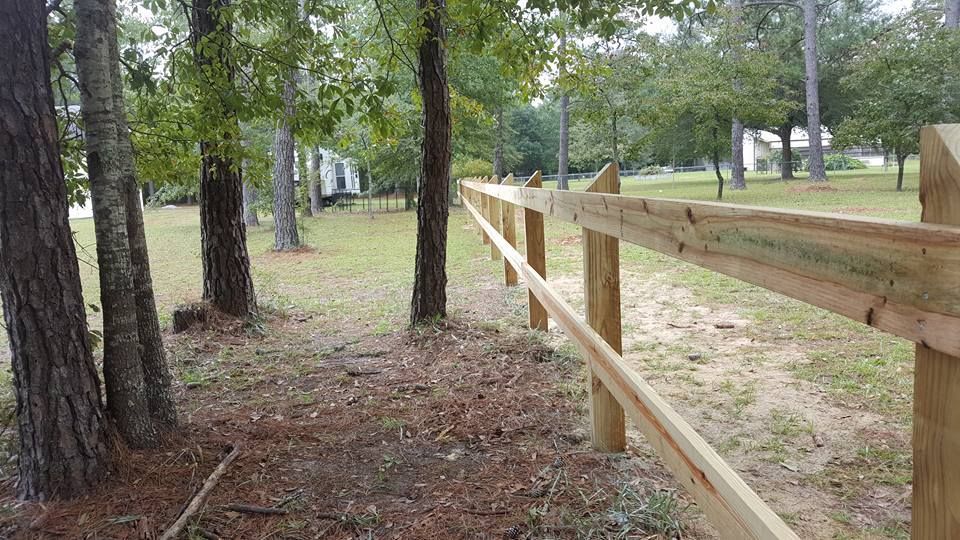 A wooden fence is surrounded by trees in a park.
