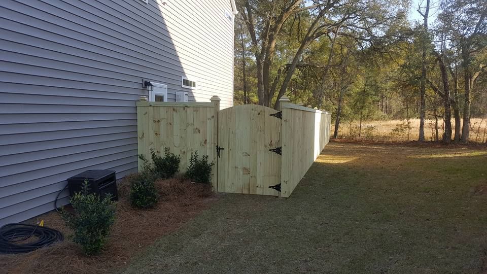 A wooden fence is sitting next to a house in a backyard.