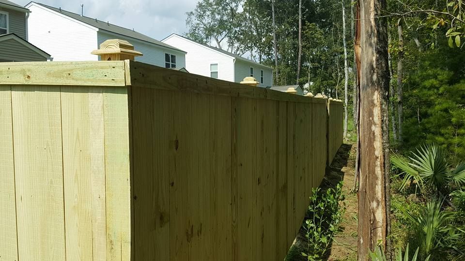 A wooden fence is surrounded by trees and houses