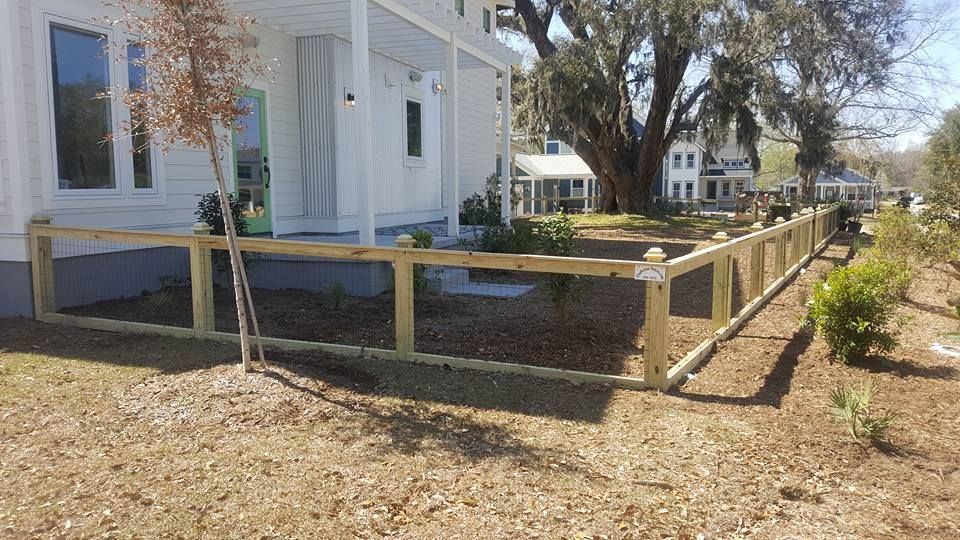 A wooden fence is in front of a white house.