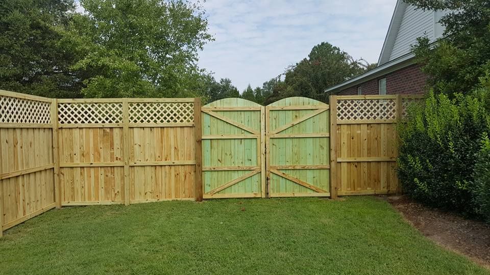 A wooden fence with a green gate in the backyard of a house.