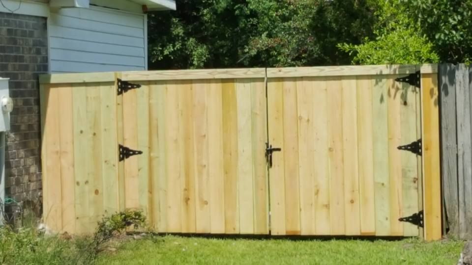 A wooden fence with a gate in front of a house.