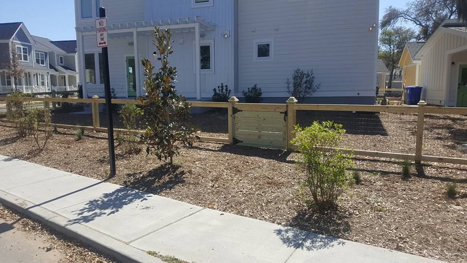 A wooden fence is in front of a white house.