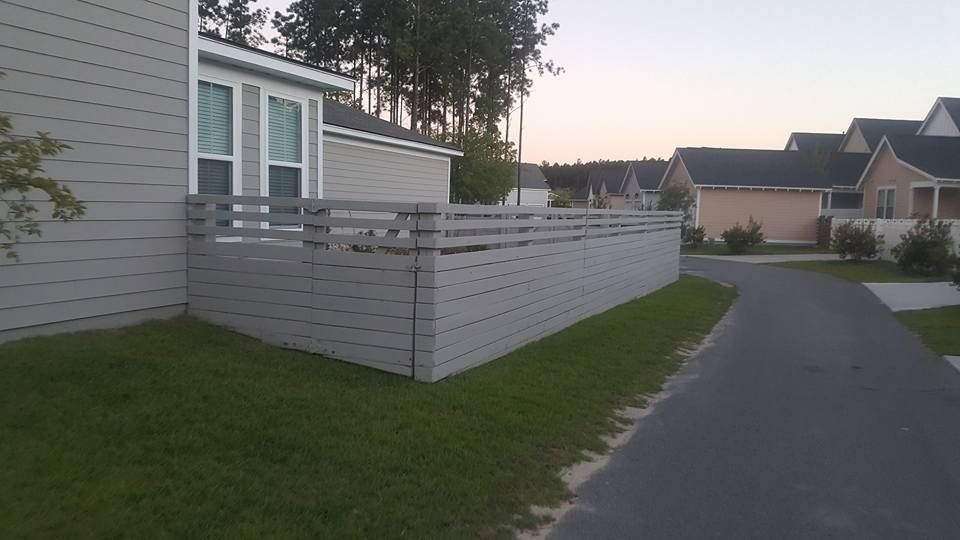 A wooden fence surrounds a house in a residential area.