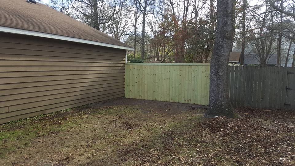 There is a wooden fence in the backyard of a house.