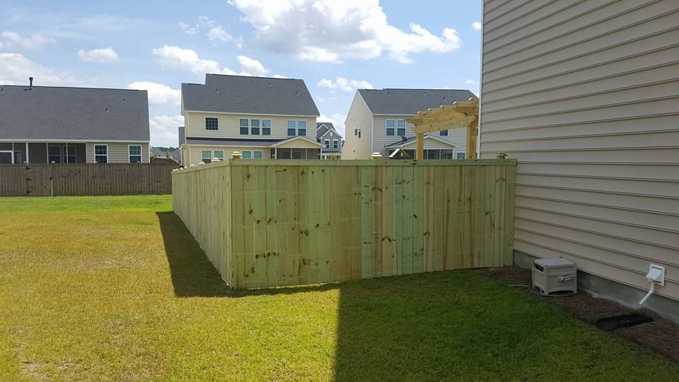 A wooden fence is in the backyard of a house.