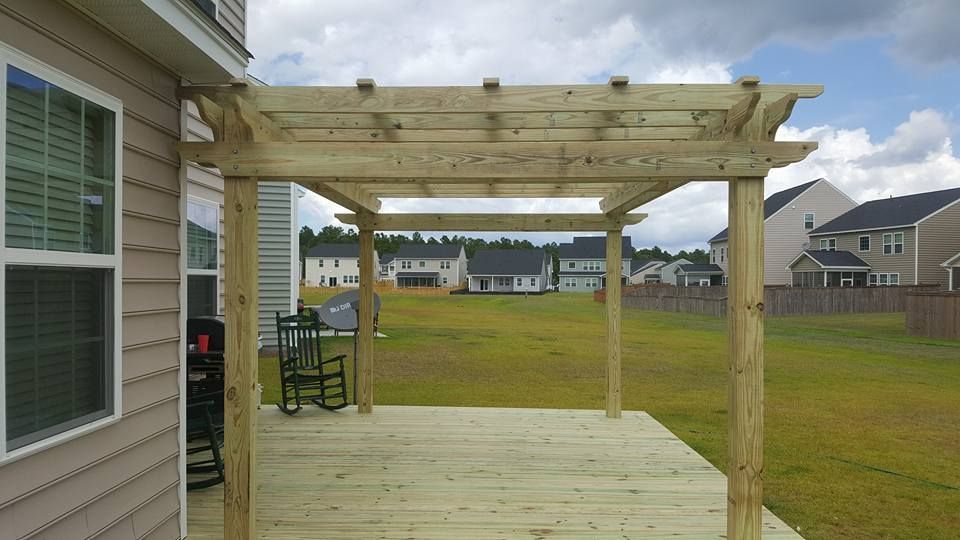 A wooden pergola is sitting on top of a wooden deck.