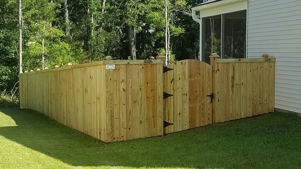 A wooden fence with a gate in the backyard of a house.