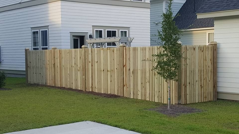 A wooden fence is in front of a white house.