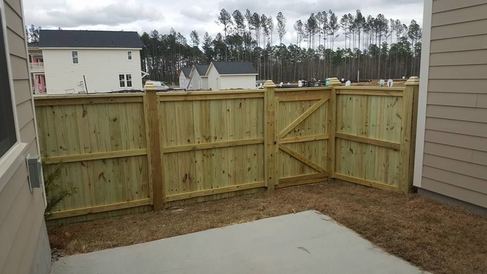 A wooden fence with a gate in the backyard of a house