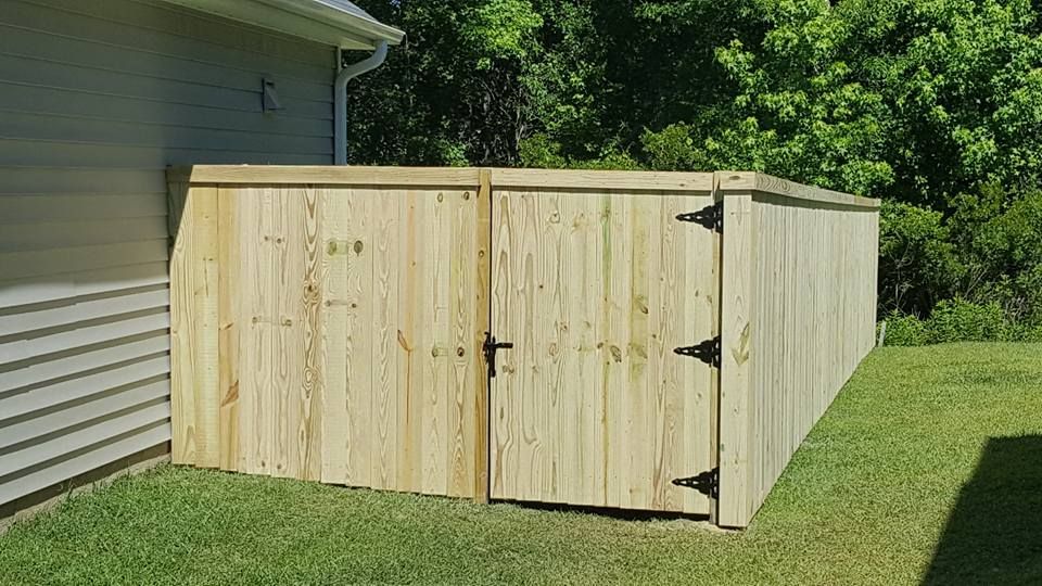 A wooden fence with a gate in the backyard of a house.