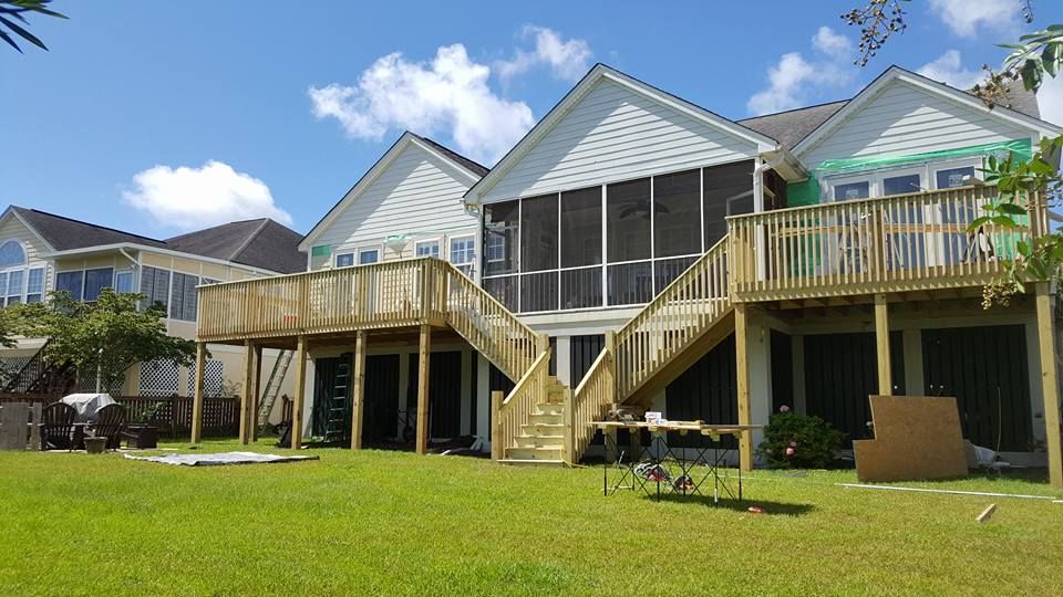 The back of a house with a screened in porch and a wooden deck.