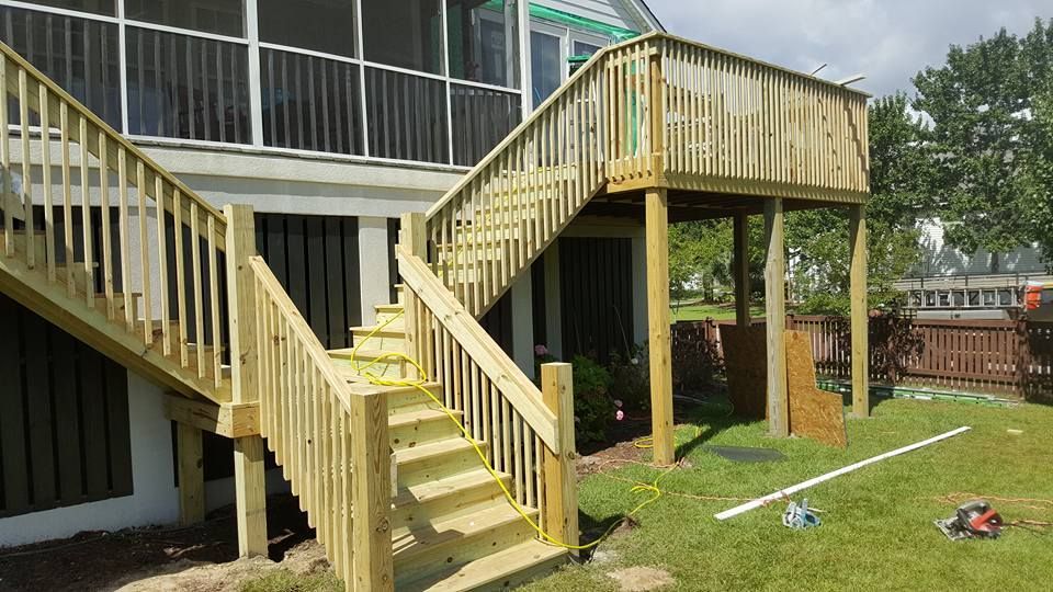 A wooden deck with stairs leading up to a screened in porch.