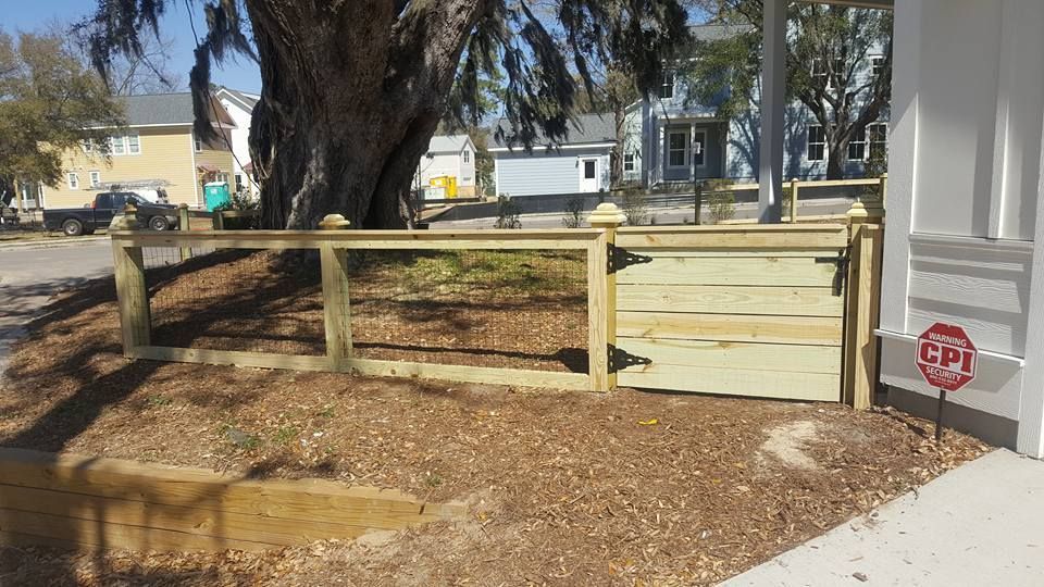 A wooden fence with a gate and a stop sign in front of a house.