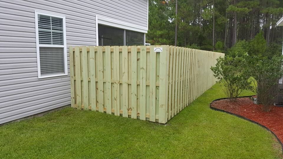 A wooden fence is in the backyard of a house.