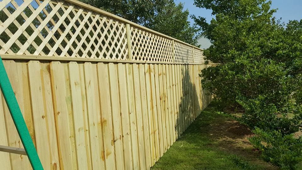 A wooden fence with a white lattice on top of it.