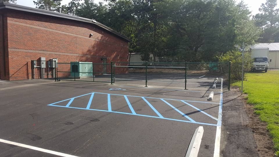 A parking lot with a handicapped parking spot and a brick building in the background