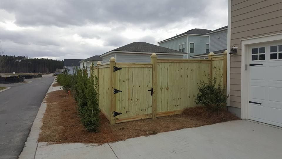 A wooden fence is sitting on the side of a street next to a garage.