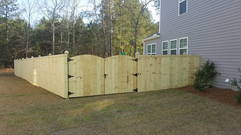 A wooden fence with a gate in the backyard of a house.