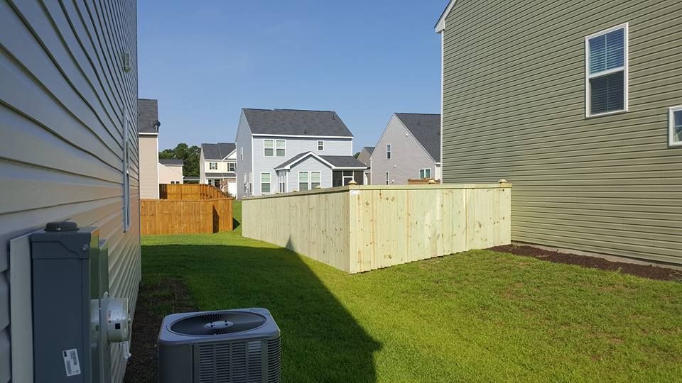 The backyard of a house with a wooden fence and an air conditioner.