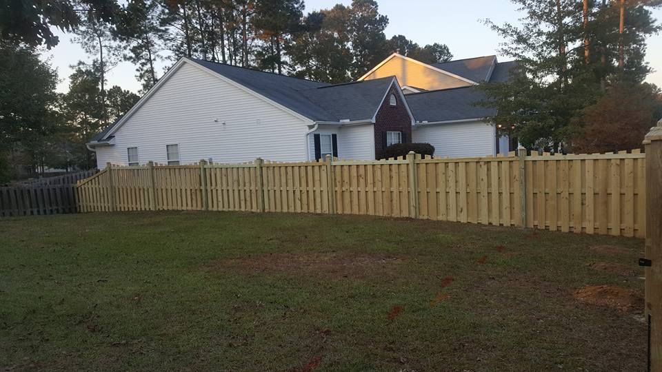 A wooden fence is in the backyard of a house.