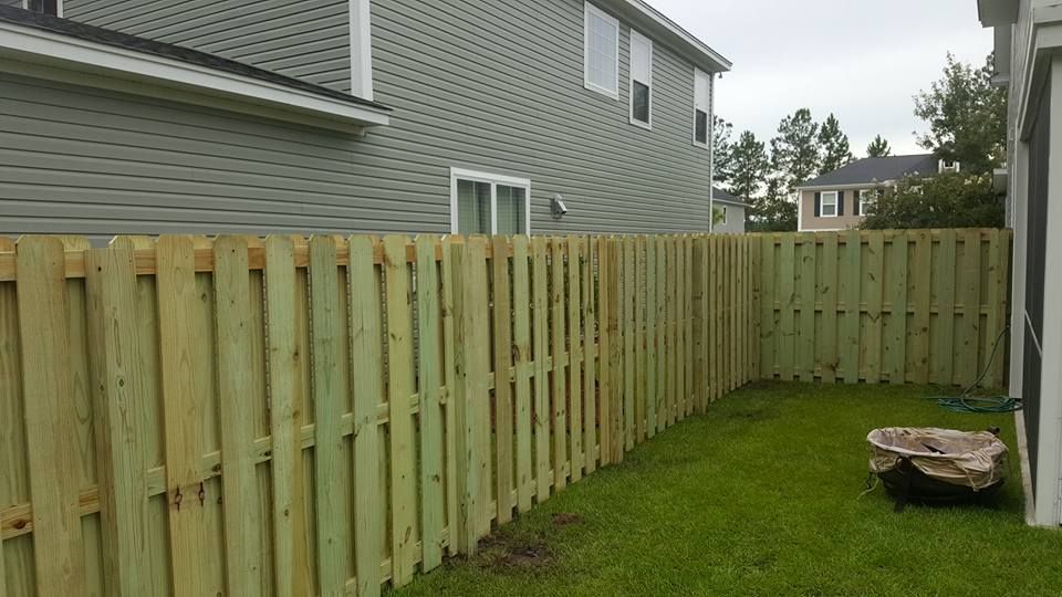 A wooden fence is in the backyard of a house.