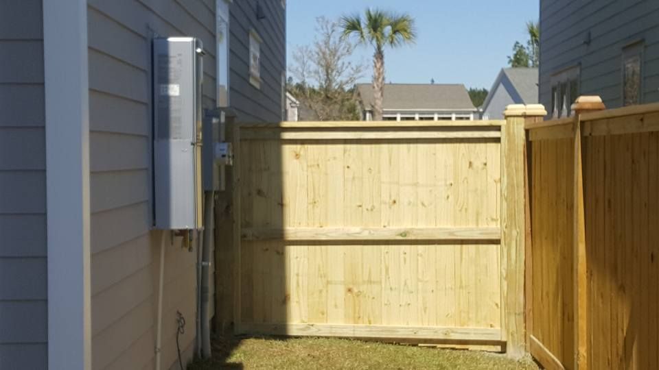 A wooden fence between two houses with a palm tree in the background.