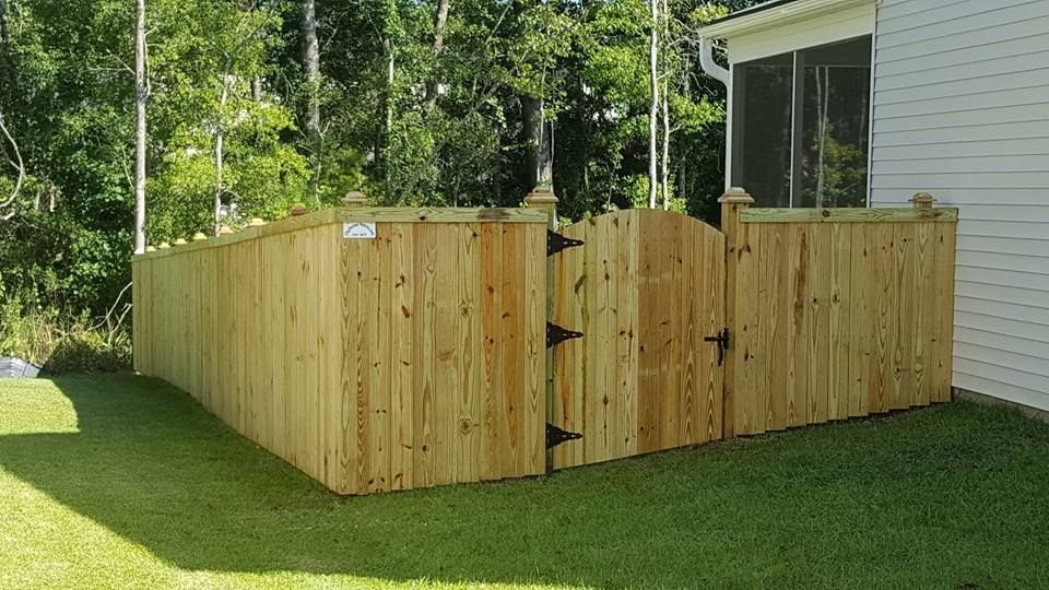 A wooden fence with a gate in the backyard of a house.