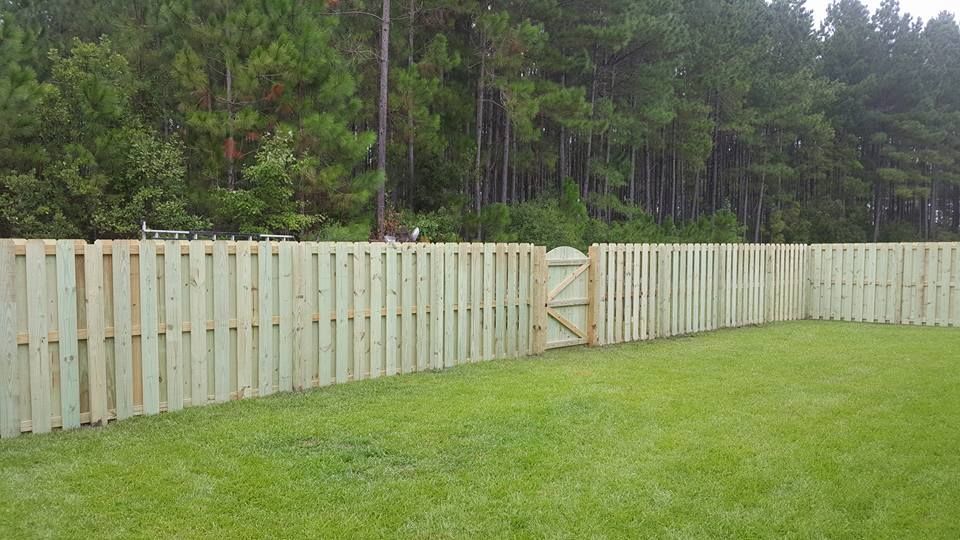 A wooden fence with a gate in the middle of a lush green field.