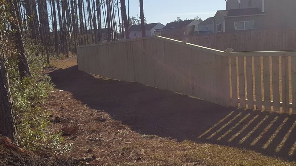 A wooden fence is surrounded by trees in a yard.