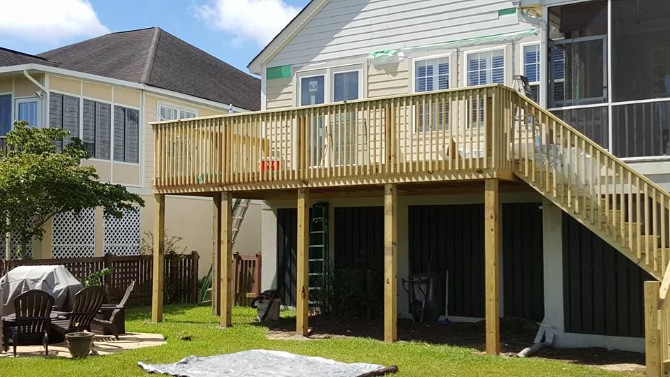 A house with a large wooden deck and stairs in the backyard.