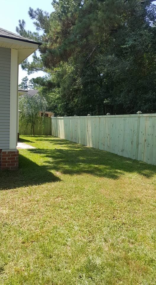 A backyard with a wooden fence and a house in the background.