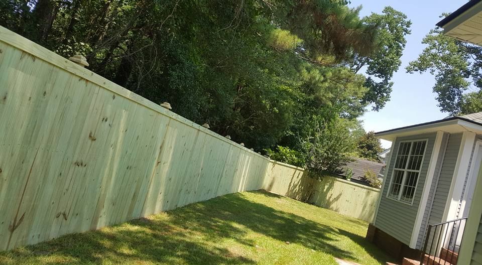 A wooden fence is in the backyard of a house.