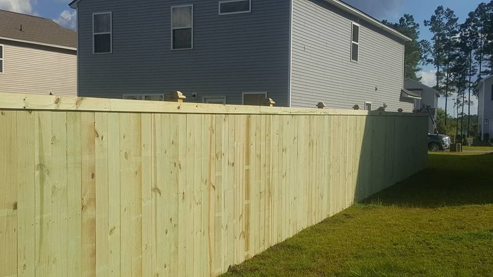 A wooden fence is in the backyard of a house.
