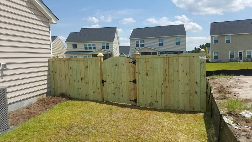 A wooden fence is in the backyard of a house.