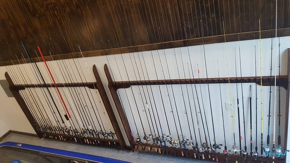 A bunch of fishing rods are hanging on a wall in a room.