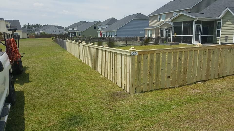 A wooden fence is in the backyard of a house.