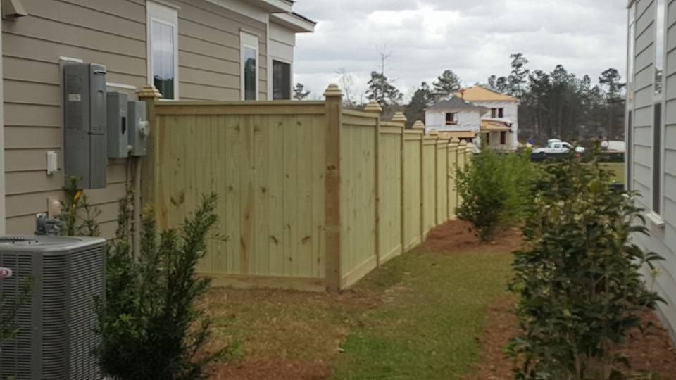 A wooden fence is in the backyard of a house.