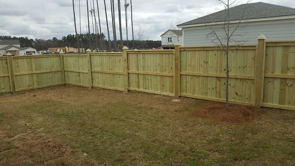 A wooden fence is in the backyard of a house.