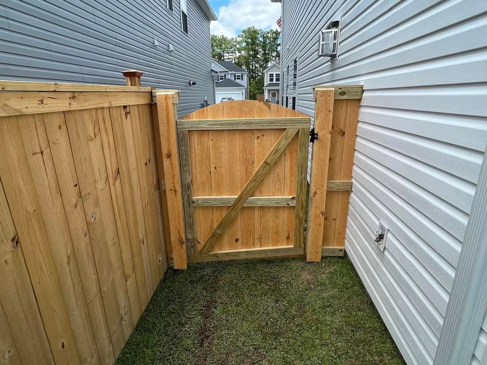 A wooden fence with a gate between two houses.
