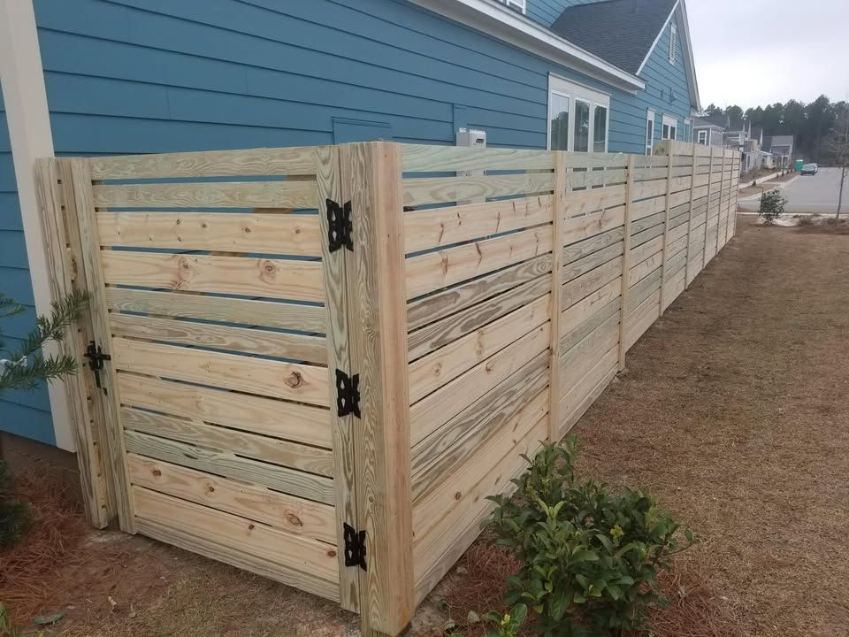 A wooden fence is in front of a blue house.