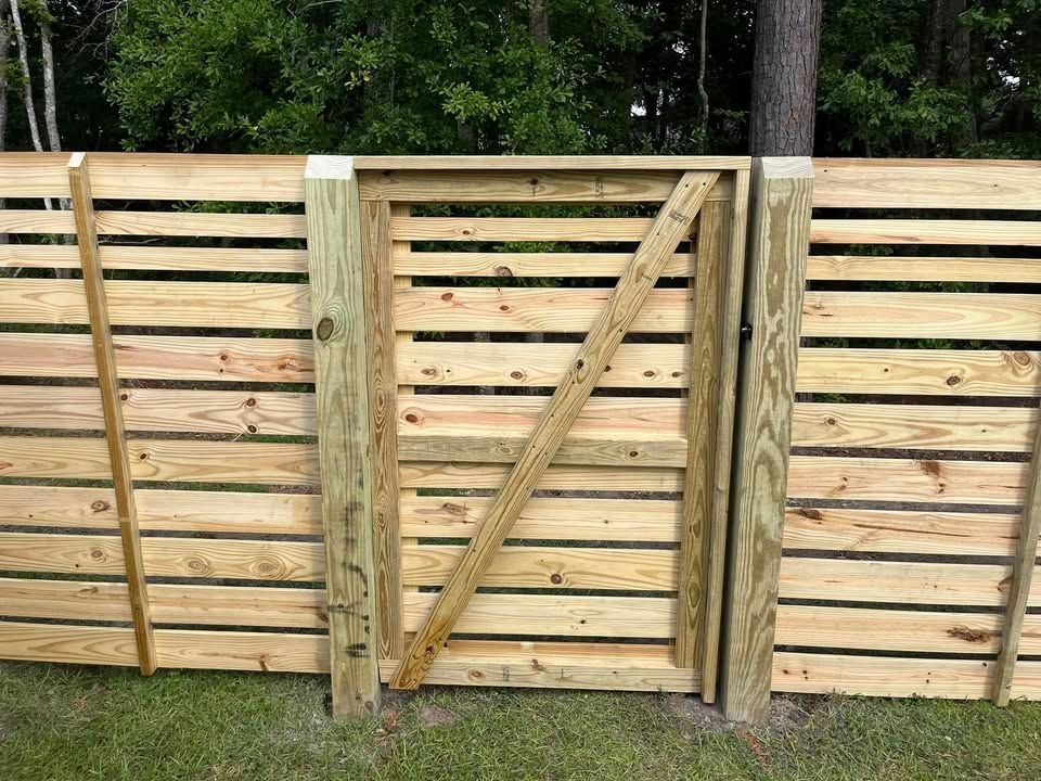 A wooden fence with a gate in the middle of it.