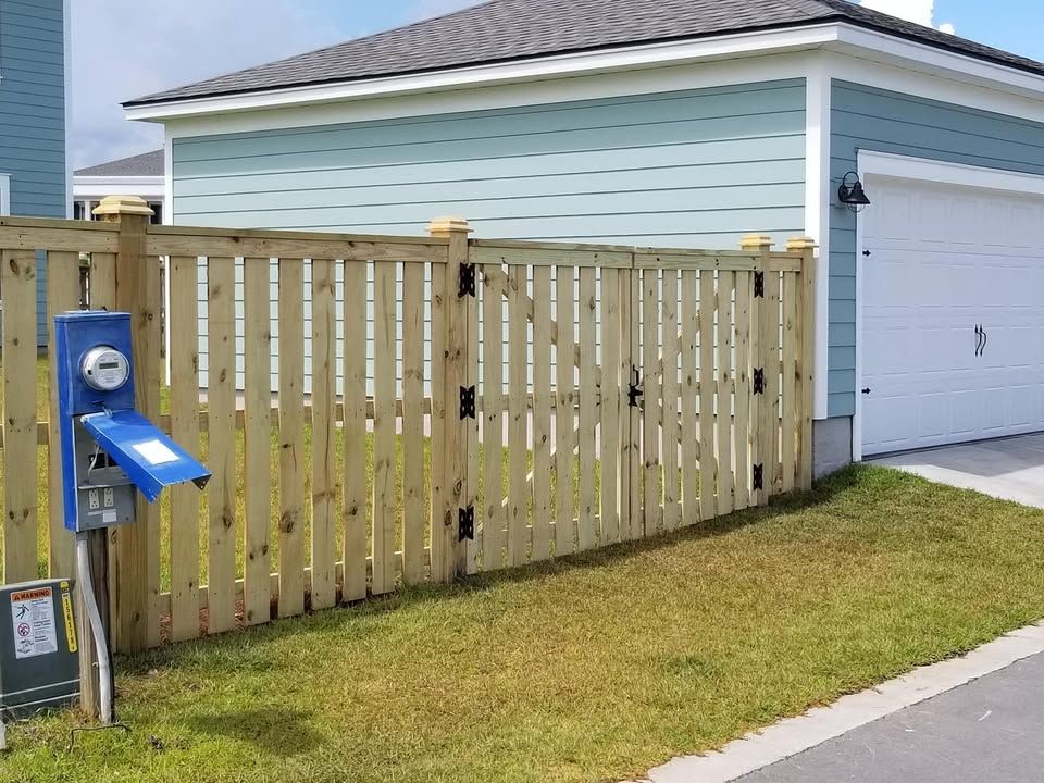 A wooden fence surrounds a garage next to a house.