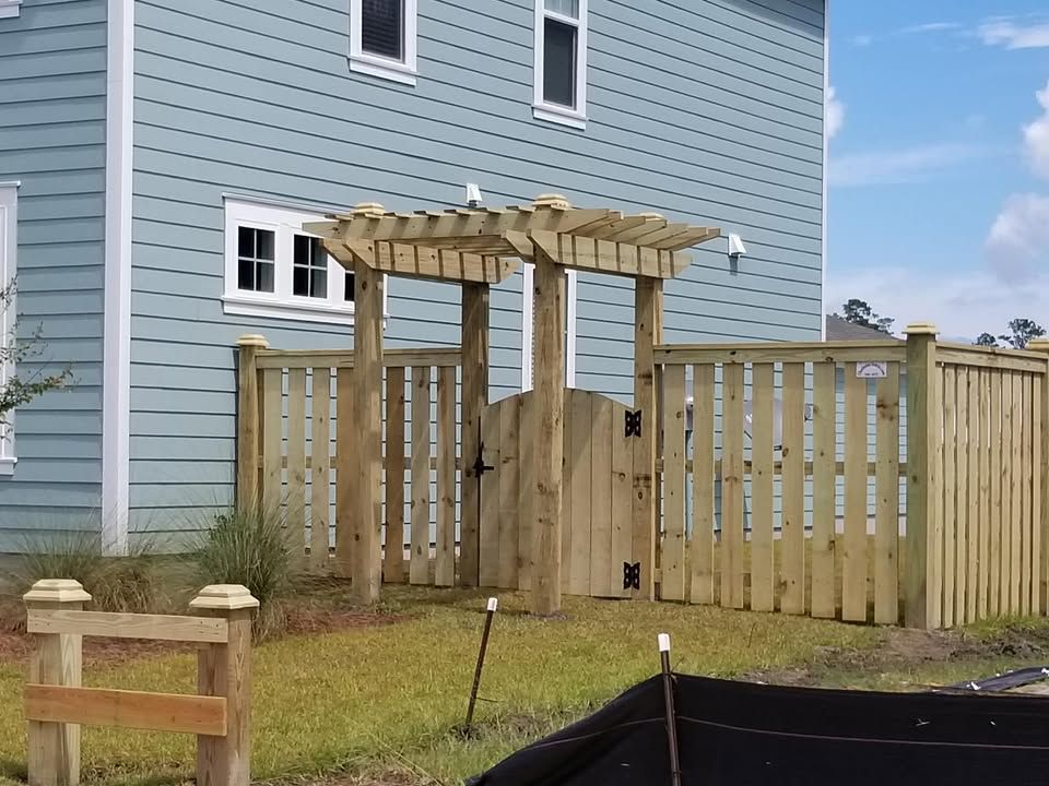 A blue house with a wooden fence and pergola in front of it