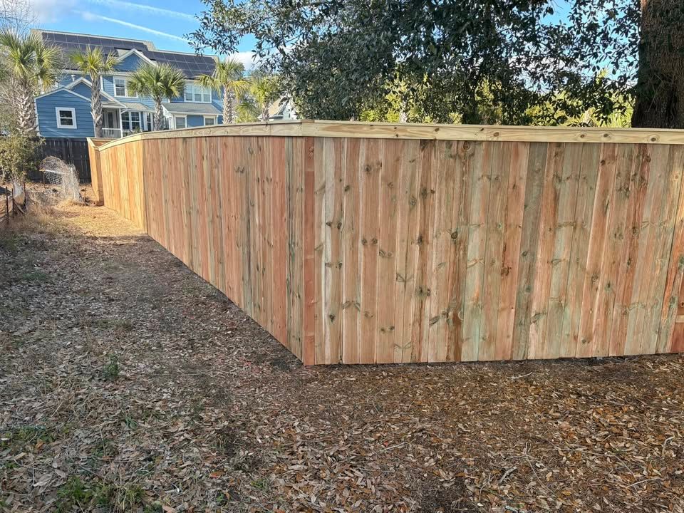 A wooden fence is in the backyard of a house.